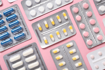 Blister packs with different pills on pink background