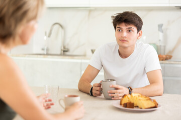 Young couple sitting at kitchen table and drinking tea at home
