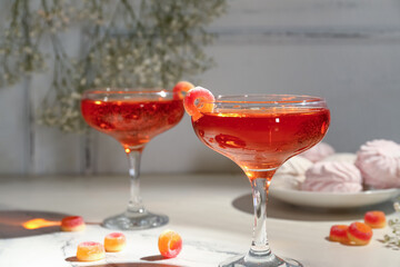 Glass of tasty cocktail with marmalade on light table, closeup. Valentine's Day celebration