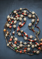 Old vintage Christmas partially broken glass beaded Tree necklace, top view on dark blue grey background, selective focuus