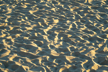 A texture of beach sand with ripples and footprints.
