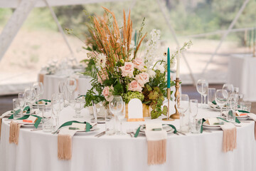 Coziness and style. Modern event design. Table setting at wedding reception. Floral compositions...