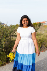 Young woman smiling, walking outdoors with wild bouquet