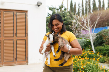 Woman holding happy baby goats in garden