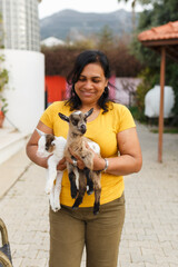 Woman holding two baby goats smiling outdoors