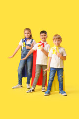 Fototapeta premium Little children dressed as superheroes with gold ribbons on color background. Childhood cancer awareness concept
