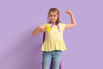 Little girl dressed as superhero with gold ribbon showing muscles on lilac background. Childhood...