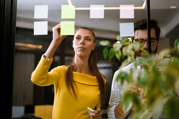 Creative brainstorming session in a modern office with colleagues collaborating on sticky notes