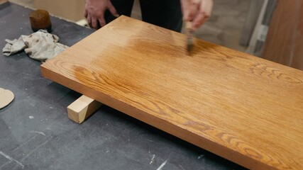 Skilled artisan applying finish to wooden surface, showcasing craftsmanship and attention to detail, camera zooms in to highlight texture and technique