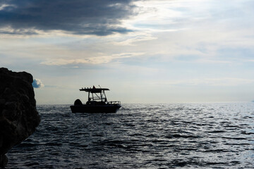 Dramatic view: silhouette of a small boat in sea near the shore on a cold evening
