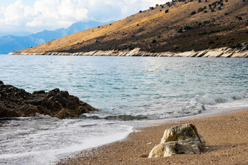 Rocks on a pebble beach in a sea bay; natural coastal landscape with copyspace