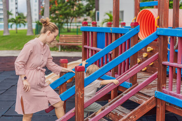 A mother playing with her young son at an outdoor playground, enjoying joyful family time and positive parenting moments. Childhood fun, bonding, laughter and carefree early years concept
