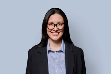 Portrait of smiling middle-aged businesswoman in black jacket on light studio background