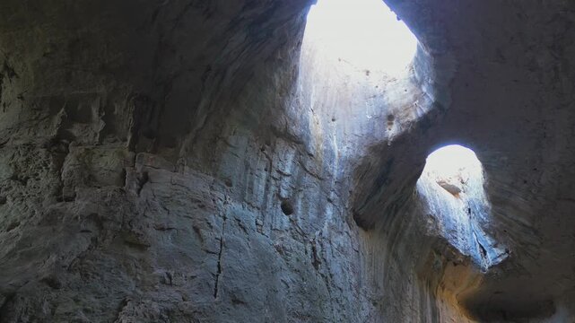 Sunlight streaming through the two large holes in the ceiling of Prohodna cave in northern Bulgaria