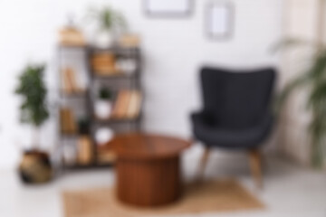 Interior of modern living room with armchair and bookshelf near white brick wall, blurred view