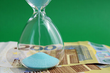 Hourglass on top of two hundred euro banknotes, time is money