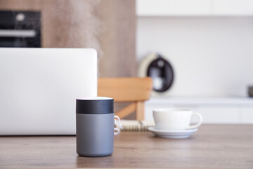 Air humidifier with laptop on table in kitchen, closeup
