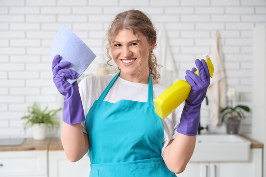 Female janitor with rag and detergent in kitchen
