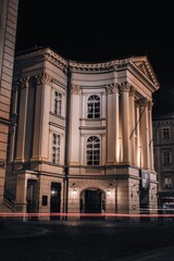 Fototapeta premium The historic Estates Theatre in Prague glowing softly at night, its neoclassical columns and elegant façade illuminated against the dark sky.