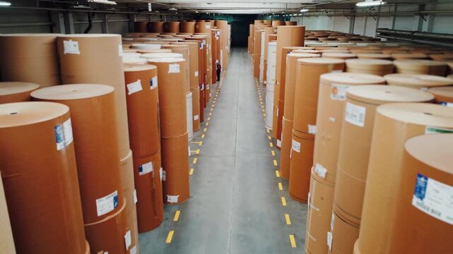 Large warehouse filled with paper rolls, Industrial warehouse housing stacked massive paper cylinders, Extensive warehouse filled with neatly arranged large cardboard rolls prepared for dispatch
