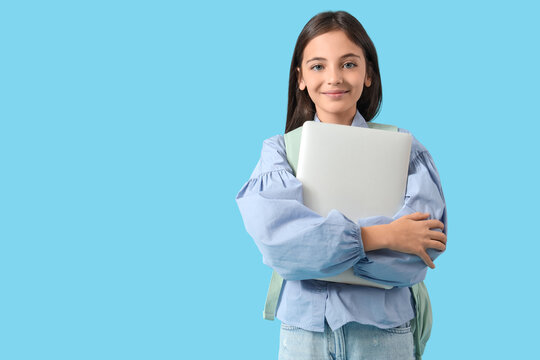 Little schoolgirl with laptop on blue background
