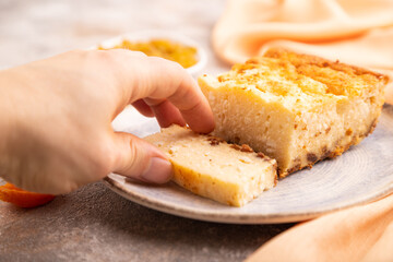 Сottage cheese Сasserole, Curd cake, with dried apricots and raisins with hand on brown concrete, side view, selective focus