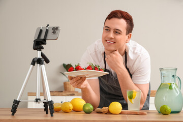 Young man recording video of him making homemade lemonade in kitchen