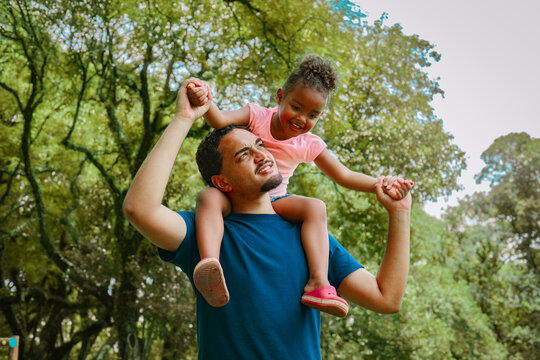 Playful father lifting his daughter at the park, enjoying a joyful family moment outdoors. Bright colors, natural light and happy childhood vibes perfect for lifestyle, parenting and family themes.