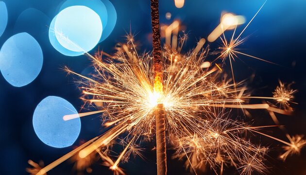close up of sparklers ignited in the dark emitting bright sparks and bokeh light effects against a blurred blue background - Powered by Adobe
