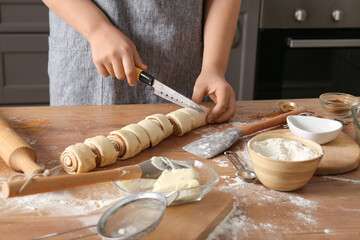 Woman preparing traditional cinnamon rolls in kitchen