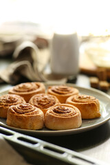 Plate with tasty baked cinnamon rolls on table in kitchen