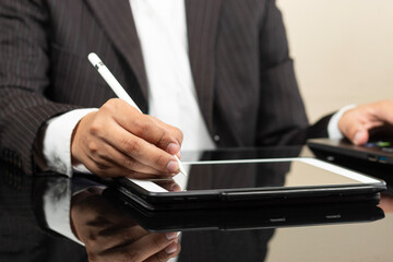 a business man on suit writing something on a tablet screen with a digital pen at the left side of the screen