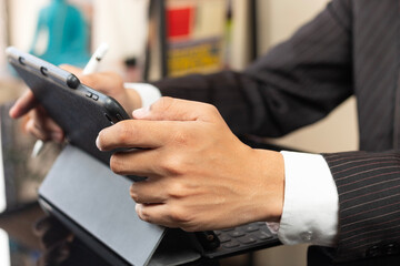 a male hands of a business man on suit using a digital tablet and working at home
