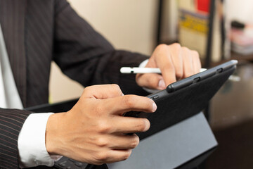 a business man on suit at the left side of the screen using a tablet