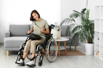 Young pretty woman in wheelchair playing on glucophone at home