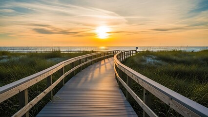 Fototapeta premium Wooden boardwalk leading to the ocean at sunset with golden light
