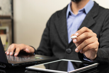 a modern business man holding a digital pen pointing to the front and over a white tablet