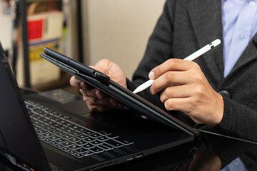 a modern business man drawing something on a tablet over a black laptop