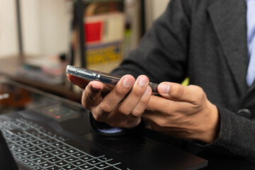 a male modern business hands holding a mobile phone over a laptop