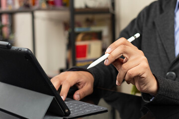 a modern business man holding a digital pen with his left hand pointing to a screen of tablet