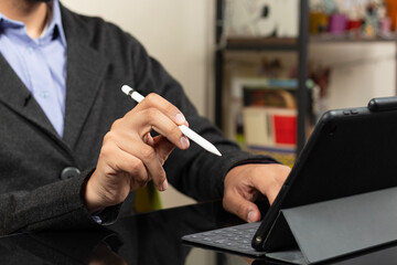 a modern business man at the left side of the screen holding a digital pen with his right hand pointing to a screen of tablet