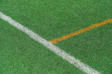 Obraz premium Green synthetic grass, artificial turf sports field with yellow and white lines.