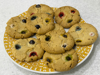 Freshly baked cookies with colorful candy pieces arranged on a decorative plate, showcasing a delightful assortment of textures and flavors perfect for dessert lovers