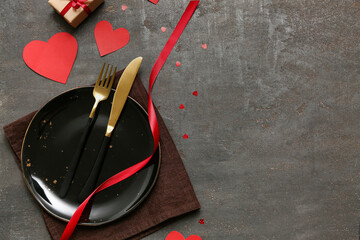 Table setting for Valentine's Day with paper hearts and red ribbon on dark background