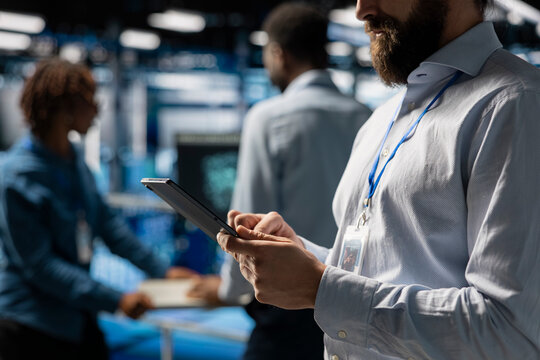 Close up of software developer using tablet to review LLM visualization with AI tools, intelligent systems for data center stability. Male engineer works on machine learning automation.