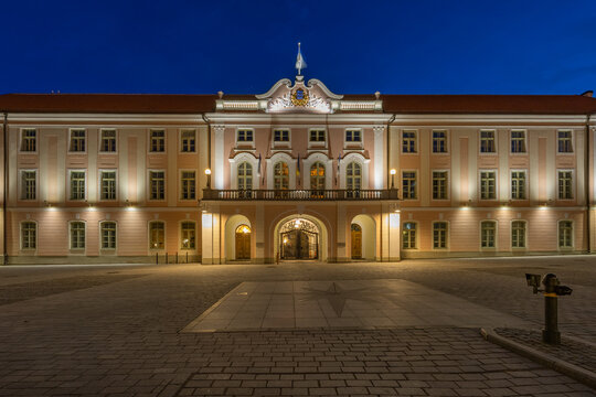 The illuminated Toompea Castle (Riigikogu - Estonian Parliament building) with its baroque facade stands majestically against a dark blue evening sky in Tallinn