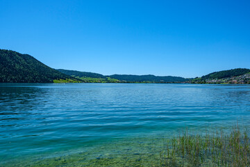 Serene Waters, Rolling Green Hills and Distant Village Under Blue Sky - Lake Aegeri, Switzerland