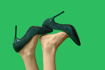 Legs of young woman in stylish green high heels on color background