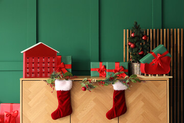 Wooden cabinet with advent calendar and Christmas decorations near green wall