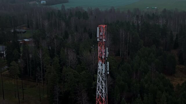 Rusty tower over serene landscape, Lattice tower situated above village and forested area amidst snow
